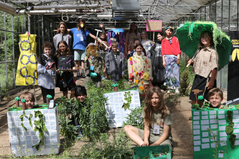 Die Schüler*innen des Workshops “FutureLeaks” posieren in ihren selbstgemachten Kostümen für ein Gruppenbild im Gewächshaus des Nachbarschaftscampus Neukölln. © HTW Berlin / Henriette Pliet