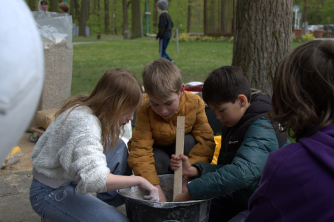 Drei Kinder mischen während eines Workshops im FEZ-Berlin Lehm für das Bauen von Ziegeln an. © HTW Berlin / Johanna Peschel