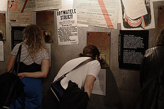 Zwei Studierende gucken sich die Ausstellung durch „Gucklöcher“ im Museum des Warschauer Aufstandes an. © HTW Berlin / Thomas Kämpfe