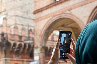 Ein Student fotografiert unter den Arkaden die markanten mittelalterlichen Türme Bolognas. © HTW Berlin/ Thomas Kämpfe