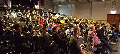 Gebanntes Publikum im großen Saal bei dem Abschluss-Panel der Studierenden unter Moderation von Judy Koke (Tag 3). © IKTf Berlin / Janosch Weiss
