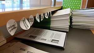 Tagungsmappen und Aufkleber für die Teilnehmer*innen. (Foto © Mirjam Ottlewski)