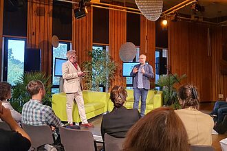 MMK-Projektleiter Prof. Dr. Nettke spricht vor den geladenen Gästen mit dem Moderator Marquinhos Markus Nichelmann über die wissenschaftliche Begleitung der Green Planet Berlin-Ausstellung. © HTW Berlin/Daniel Puster